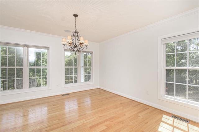 unfurnished dining area featuring a notable chandelier, hardwood / wood-style floors, and crown molding