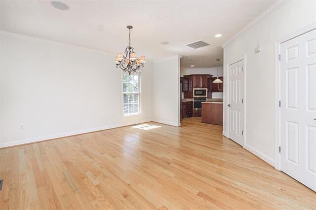 unfurnished living room featuring crown molding, a notable chandelier, and light hardwood / wood-style flooring