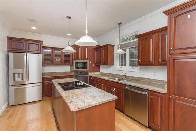 kitchen featuring light hardwood / wood-style floors, appliances with stainless steel finishes, pendant lighting, and a kitchen island