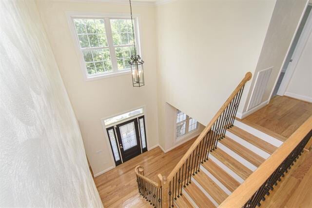 interior space with an inviting chandelier, crown molding, and light wood-type flooring