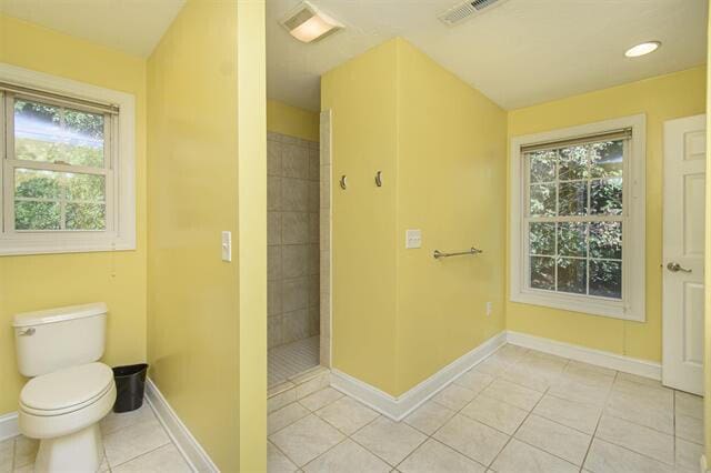 bathroom featuring tile patterned flooring, toilet, and tiled shower