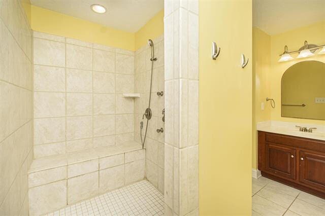 bathroom featuring vanity, a tile shower, and tile patterned floors