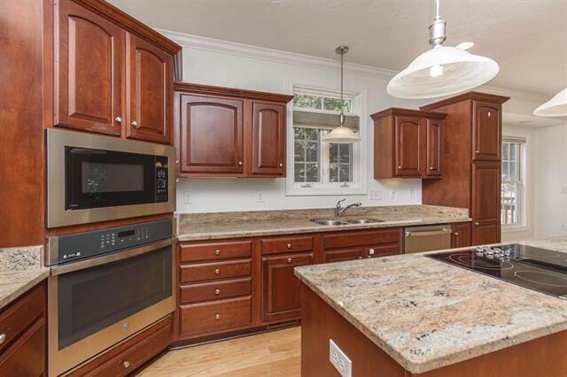 kitchen featuring stainless steel appliances, ornamental molding, sink, pendant lighting, and light hardwood / wood-style floors