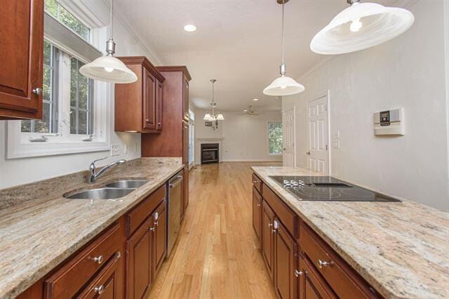 kitchen featuring light stone counters, sink, hanging light fixtures, and light wood-type flooring