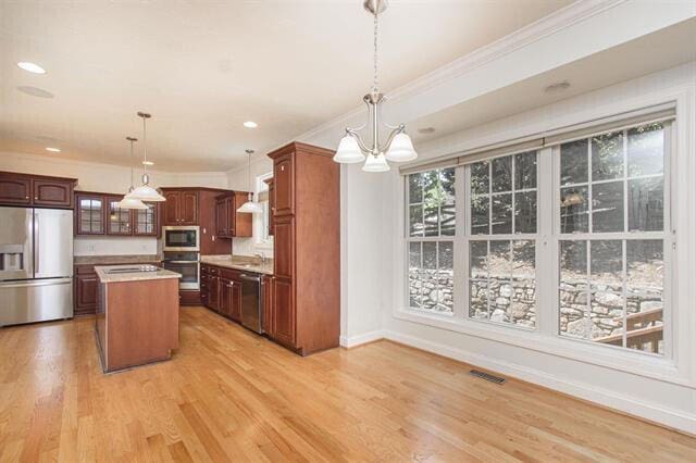 kitchen featuring a kitchen island, appliances with stainless steel finishes, hanging light fixtures, and a healthy amount of sunlight