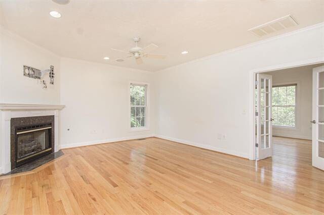 unfurnished living room with a high end fireplace, light hardwood / wood-style flooring, and plenty of natural light