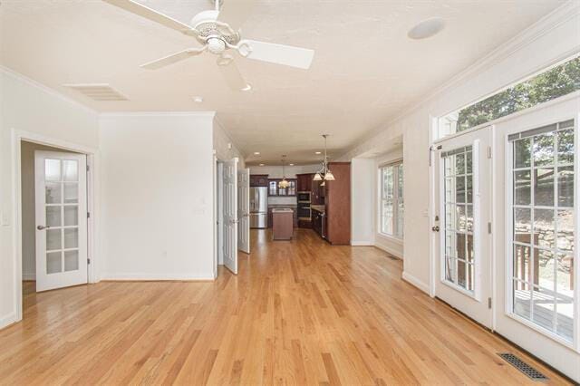 unfurnished living room featuring light hardwood / wood-style floors, crown molding, and a wealth of natural light