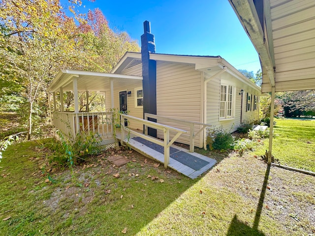 view of side of home with covered porch and a lawn