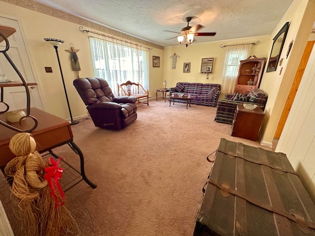 carpeted living room featuring ceiling fan and a textured ceiling