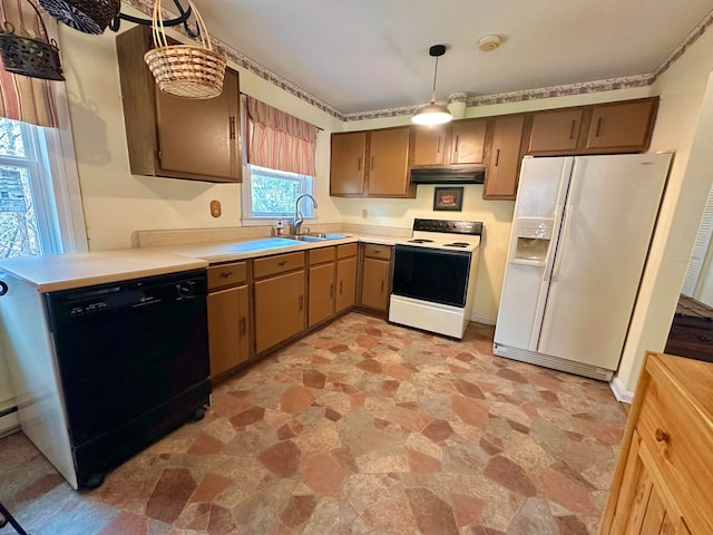 kitchen featuring decorative light fixtures, white appliances, and sink