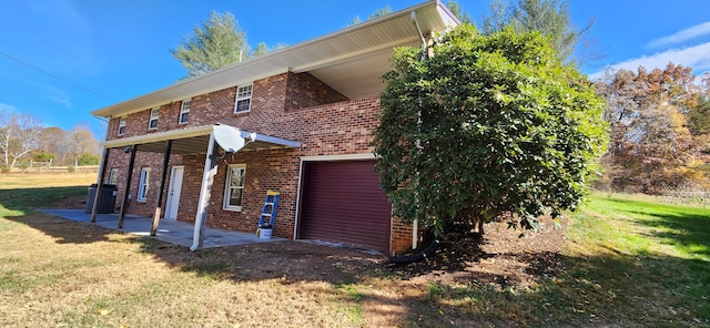 exterior space with a garage, a lawn, central AC, and a patio area