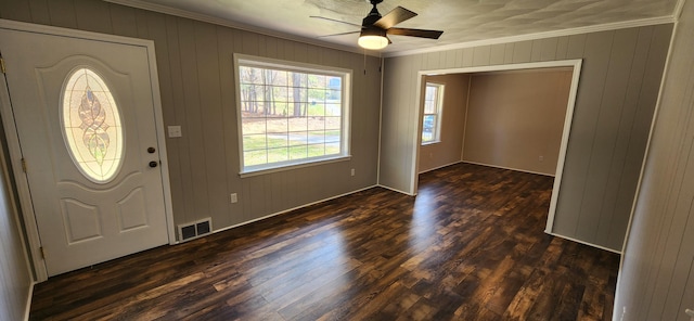 foyer entrance featuring dark hardwood / wood-style flooring, wooden walls, ceiling fan, and crown molding