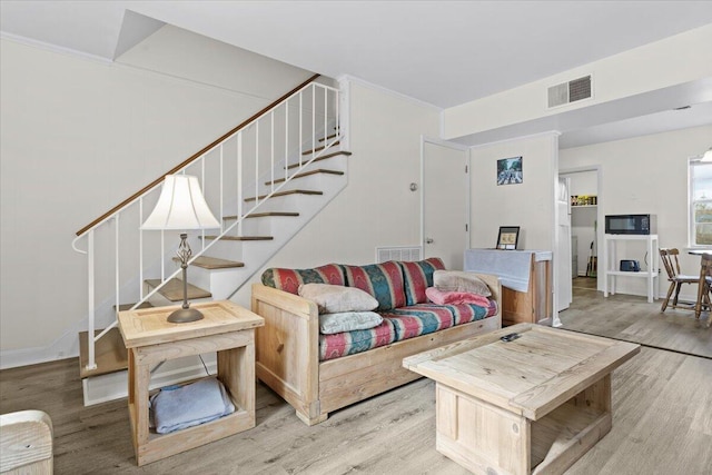 living room featuring light wood-type flooring and crown molding