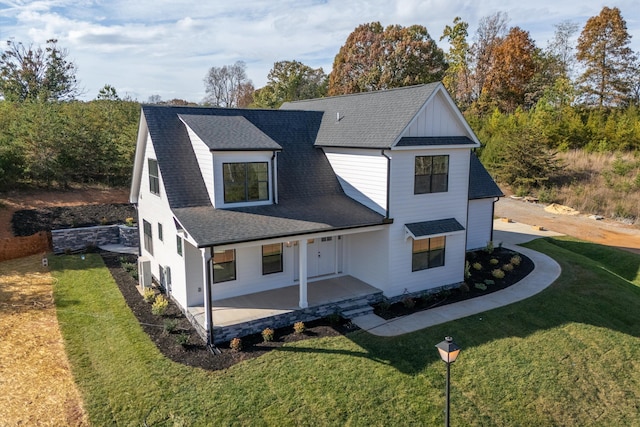view of front of property with a front lawn, a shingled roof, and covered porch