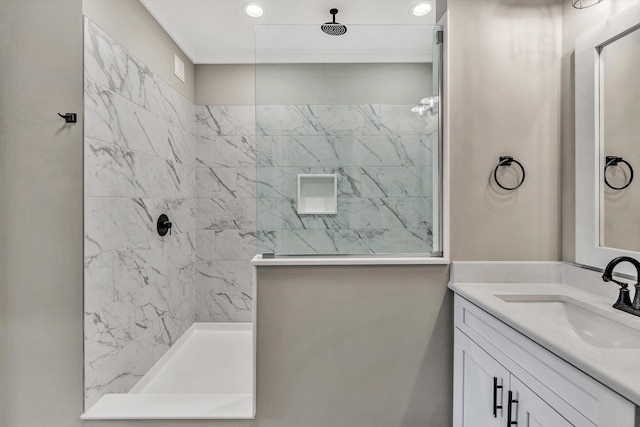 bathroom with tiled shower and vanity