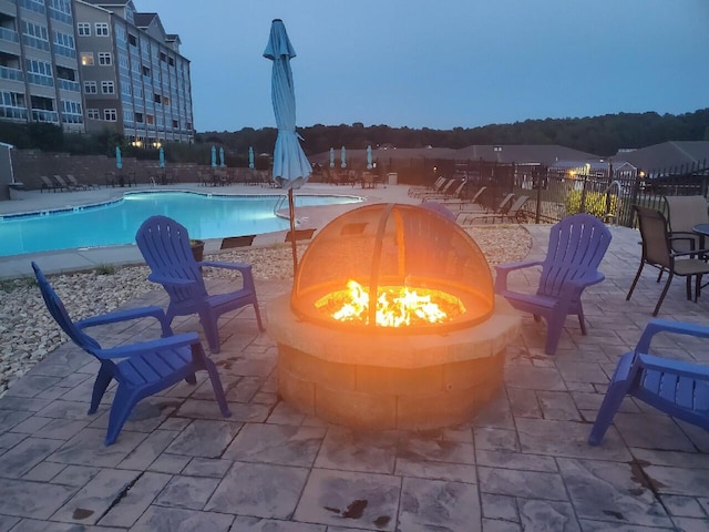 pool at dusk featuring a patio and an outdoor fire pit