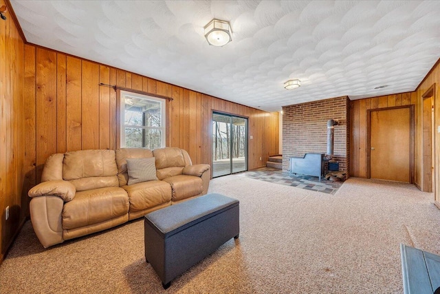 living room featuring carpet, a wood stove, and wooden walls