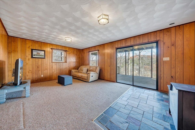 unfurnished living room featuring carpet flooring and wood walls