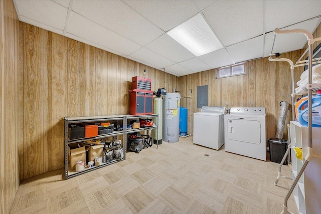 laundry room featuring washing machine and clothes dryer, water heater, wooden walls, and light parquet floors