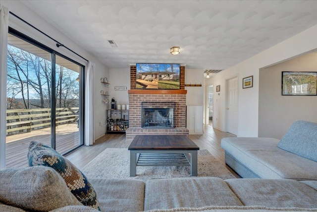 living room with light wood-type flooring and a brick fireplace