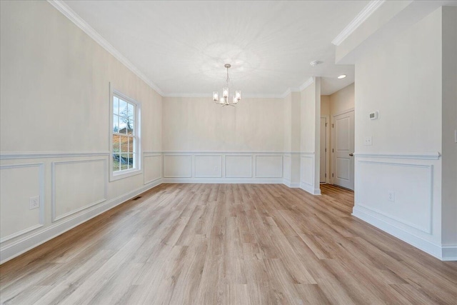 spare room featuring light hardwood / wood-style floors, a notable chandelier, and crown molding