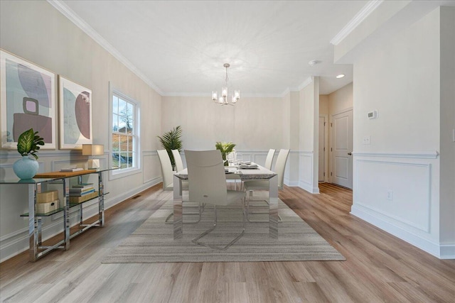 dining room with ornamental molding, a notable chandelier, and light hardwood / wood-style floors