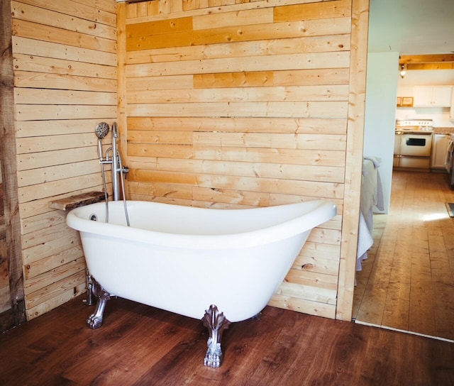 bathroom with a tub to relax in, wooden walls, and wood-type flooring