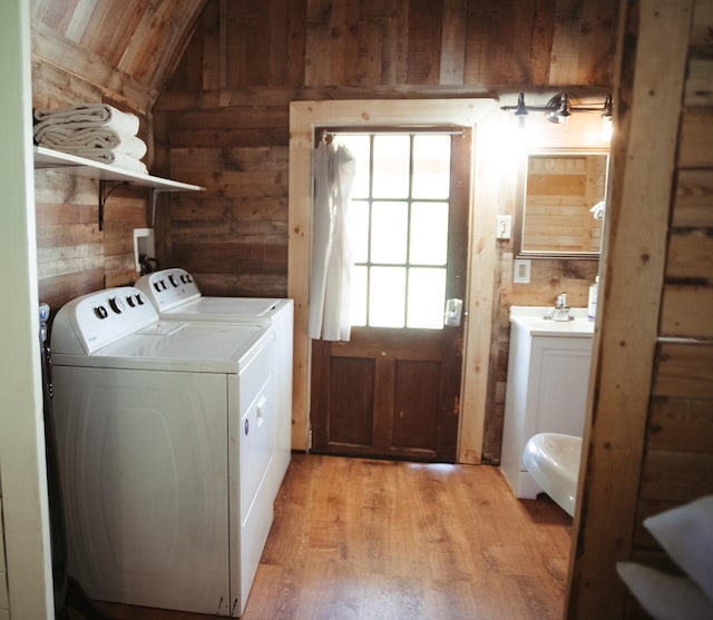 clothes washing area with washer and clothes dryer and light hardwood / wood-style flooring