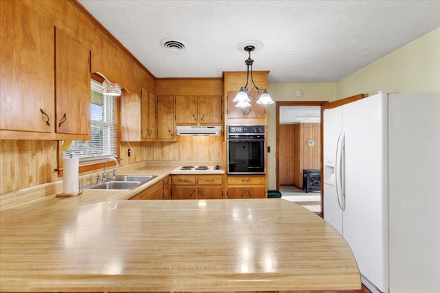 kitchen featuring sink, kitchen peninsula, a textured ceiling, decorative light fixtures, and white appliances