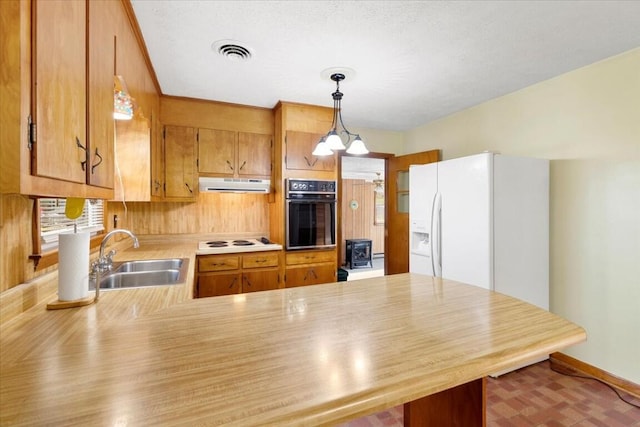 kitchen featuring sink, an inviting chandelier, kitchen peninsula, pendant lighting, and white appliances