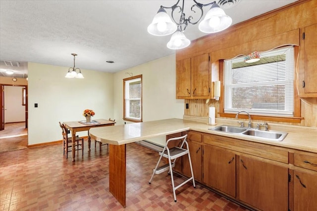 kitchen featuring a wealth of natural light, a chandelier, sink, and hanging light fixtures