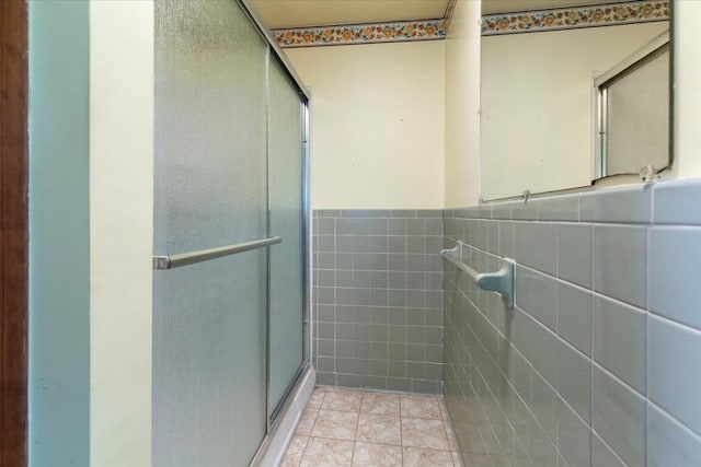 bathroom with tile patterned floors, tile walls, and a shower with shower door