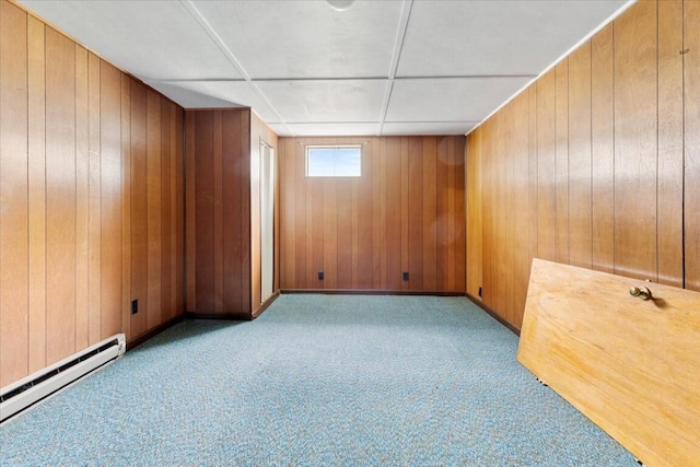 carpeted spare room featuring wooden walls and a baseboard radiator