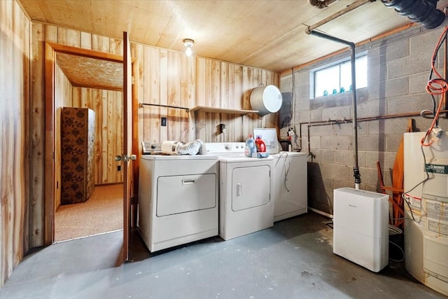 washroom featuring electric water heater, separate washer and dryer, and wood walls