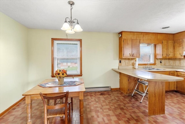 kitchen featuring sink, a baseboard radiator, kitchen peninsula, decorative light fixtures, and a breakfast bar area