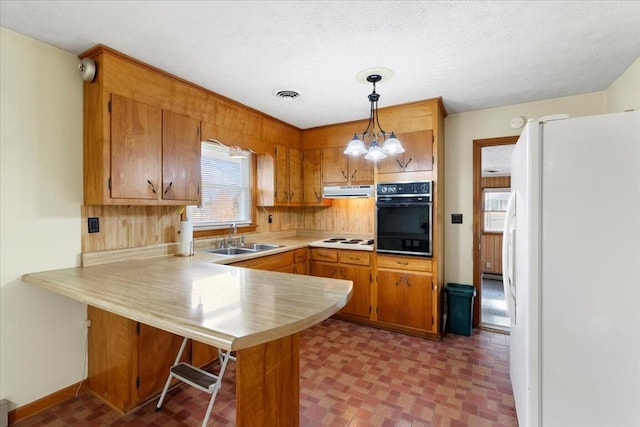 kitchen featuring pendant lighting, white appliances, sink, a kitchen bar, and kitchen peninsula