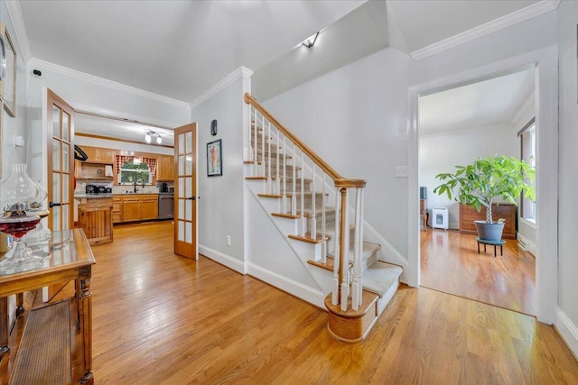 stairway with french doors, hardwood / wood-style floors, sink, and crown molding