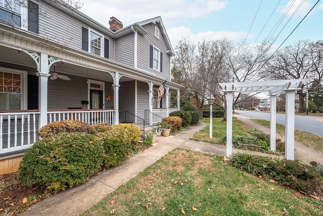 view of side of home featuring a pergola, a yard, and covered porch