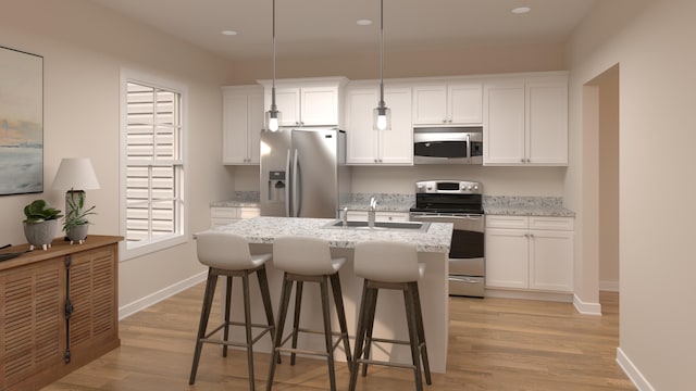 kitchen with light wood finished floors, a sink, a breakfast bar area, appliances with stainless steel finishes, and a kitchen island with sink