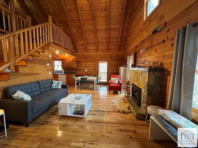 living room featuring vaulted ceiling with beams, a wealth of natural light, wood ceiling, and light hardwood / wood-style floors