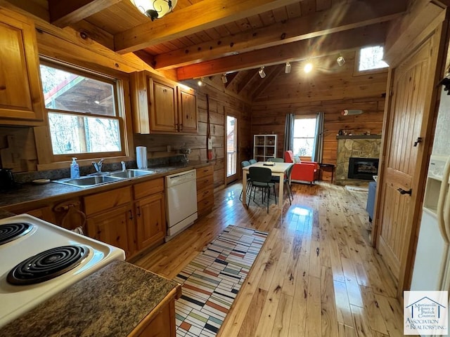 kitchen featuring wood walls, sink, light wood-type flooring, lofted ceiling with beams, and white appliances