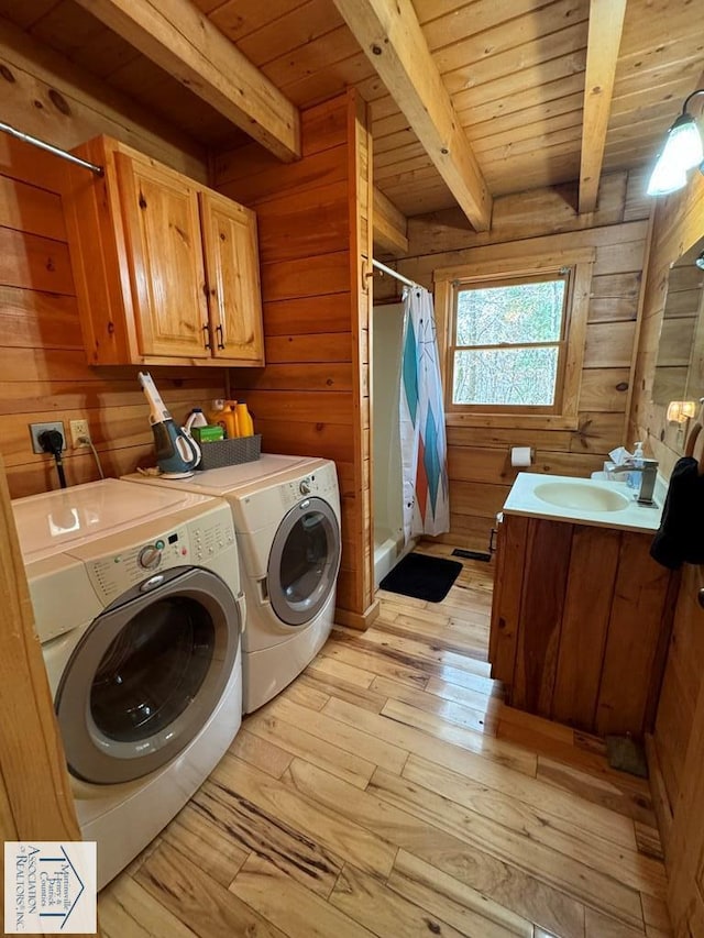 laundry area with cabinets, light hardwood / wood-style floors, wooden walls, and washer and clothes dryer