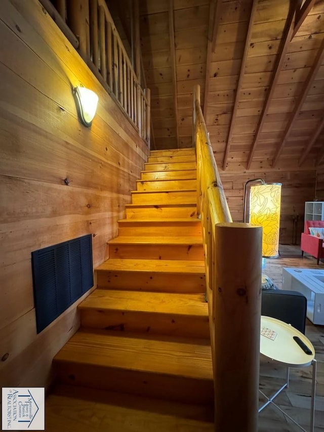 stairs featuring beamed ceiling, wooden walls, and wood ceiling