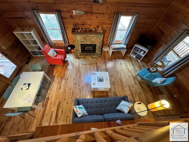 unfurnished living room with wood-type flooring, vaulted ceiling, a healthy amount of sunlight, and a fireplace