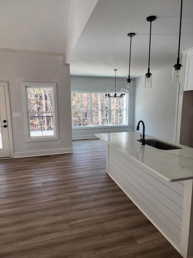 kitchen featuring pendant lighting, dark hardwood / wood-style flooring, white cabinetry, and light stone countertops