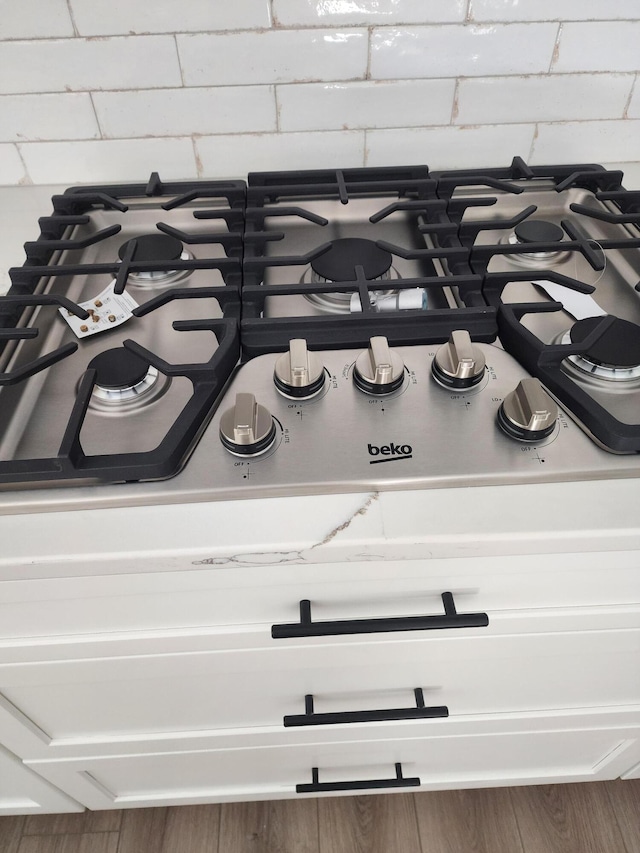 details with hardwood / wood-style floors and stainless steel gas stovetop