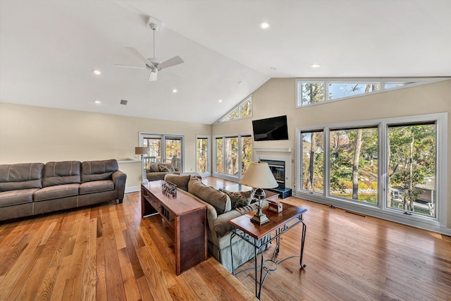 living room featuring light wood-type flooring, ceiling fan, and high vaulted ceiling