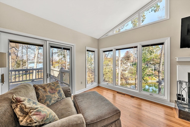 sunroom with a wealth of natural light, lofted ceiling, and a water view