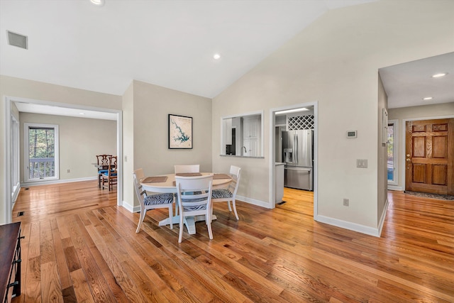 dining area featuring light hardwood / wood-style flooring and high vaulted ceiling