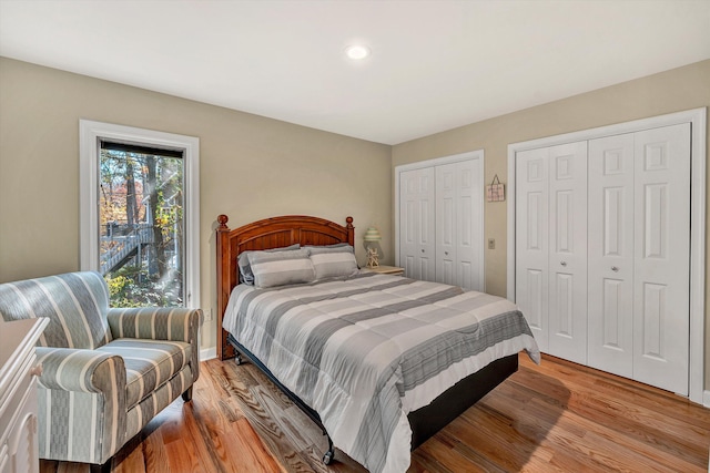 bedroom with light hardwood / wood-style flooring and two closets